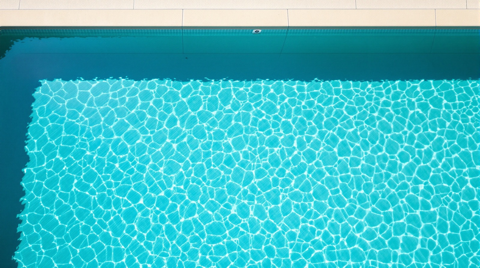 Clear residential swimming pool water in morning light, seen from above